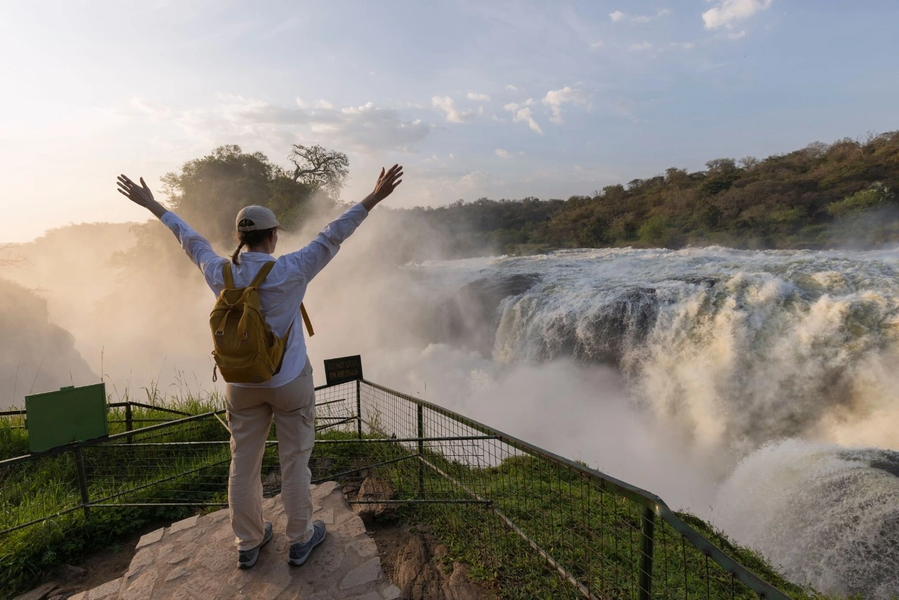 Traveler enjoying the breathtaking view and thunderous sound at the top of Murchison Falls during an 11-day Uganda safari featuring gorilla trekking, chimpanzee tracking, and Murchison Falls National Park adventure.