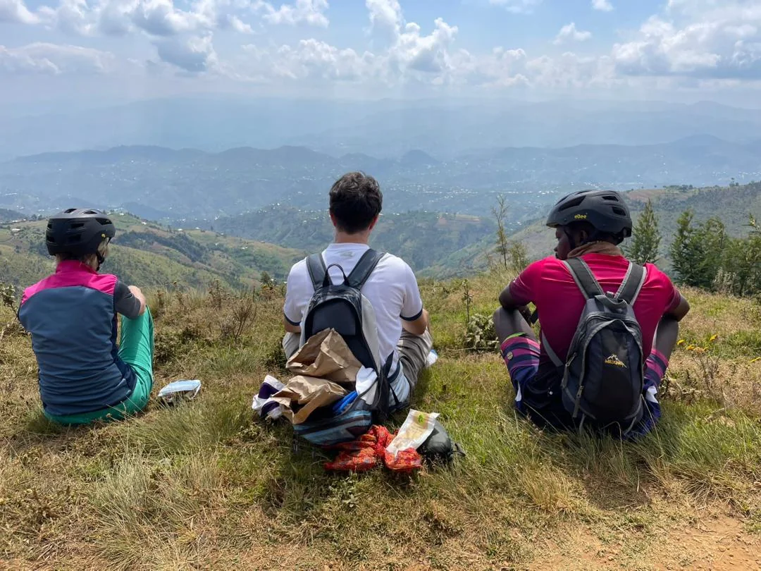 Travelers taking a scenic rest stop during an 8-Day Rwanda Gravel Cycling Adventure on the Congo Nile Trail, enjoying panoramic views of Rwanda's lush green hills and experiencing the country's breathtaking landscapes and cultural journey.