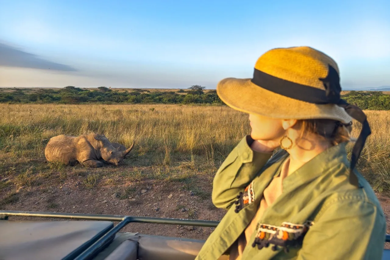 Girl traveler on safari in Serengeti National Park spotting a rhino during game drive adventure