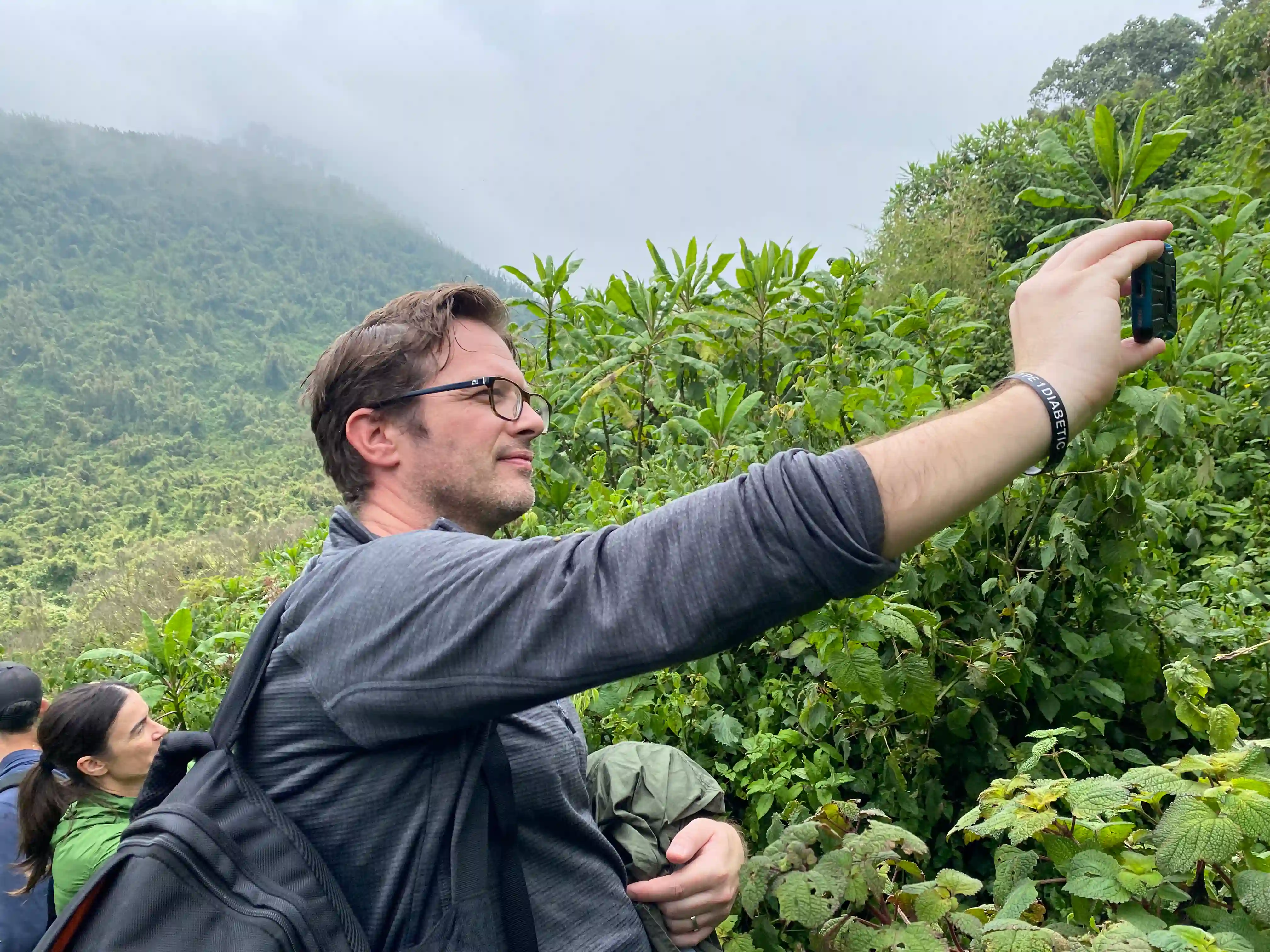 A smiling guest takes a selfie while exploring the lush forests of Volcanoes National Park, surrounded by dense greenery and the scenic volcanic landscape that makes the park one of Rwanda’s most iconic wildlife and nature destinations.