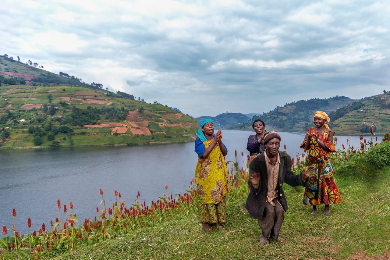 Batwa community with visitors experiencing cultural dances at the shores of lake Bunyonyi. 