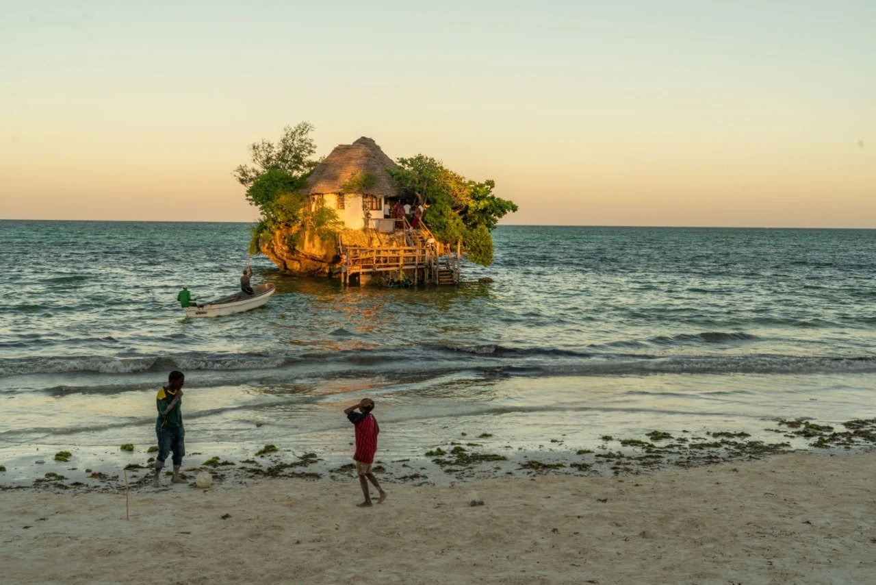 Iconic Zanzibar beach restaurant at sunset with wooden deck over turquoise ocean — How To Visit & Experience Zanzibar: Ultimate Travel Guide.