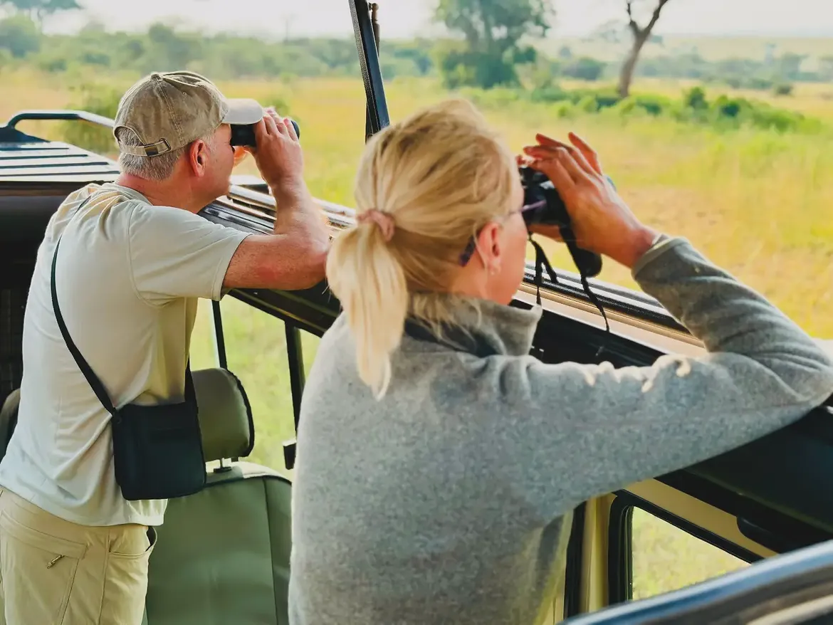Guests watching the Great Wildebeest Migration in the central Serengeti National Park during April as herds graze across the lush green plains after the long rains in Tanzania.