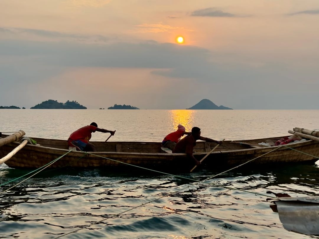 Local fishermen paddling a traditional boat on Lake Kivu along the scenic Congo Nile Trail in Rwanda, showcasing authentic local life and adventure tourism.